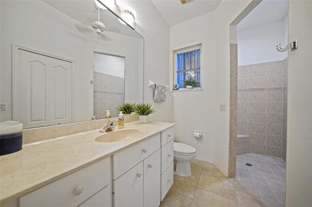 bathroom with tile patterned flooring, vanity, tiled shower, and toilet