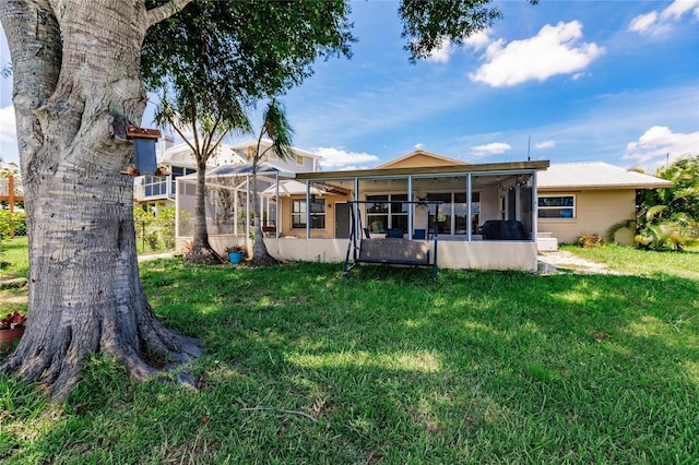 rear view of property with a yard, a lanai, and a sunroom