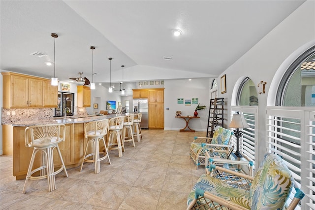 kitchen with pendant lighting, stainless steel fridge, light stone counters, tasteful backsplash, and vaulted ceiling