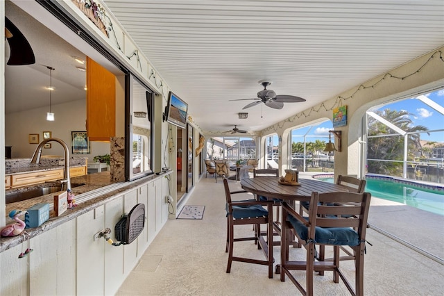 view of patio / terrace featuring sink, ceiling fan, and glass enclosure