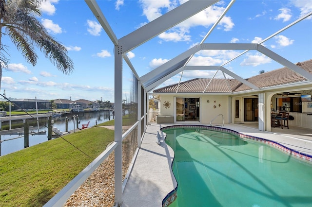 view of pool with a water view, a yard, a lanai, ceiling fan, and a patio