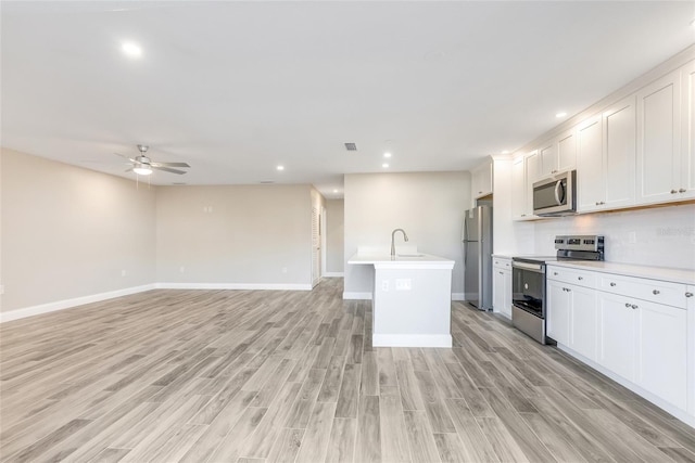 kitchen featuring stainless steel appliances, an island with sink, white cabinets, and light hardwood / wood-style floors