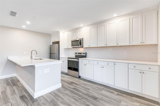 kitchen featuring appliances with stainless steel finishes, a kitchen breakfast bar, sink, and white cabinets