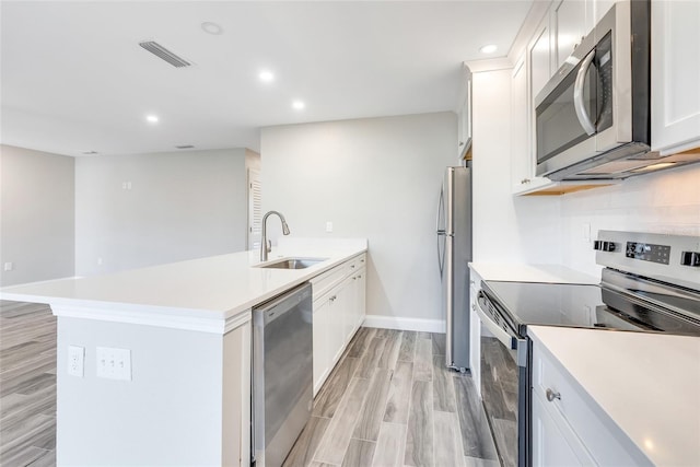 kitchen featuring sink, tasteful backsplash, light wood-type flooring, appliances with stainless steel finishes, and white cabinets