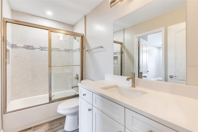 full bathroom with bath / shower combo with glass door, wood-type flooring, vanity, and toilet