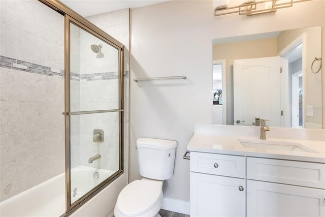 full bathroom with enclosed tub / shower combo, vanity, and toilet