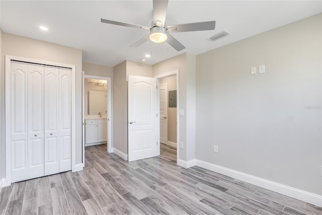 unfurnished bedroom featuring ceiling fan, electric panel, a closet, and light wood-type flooring