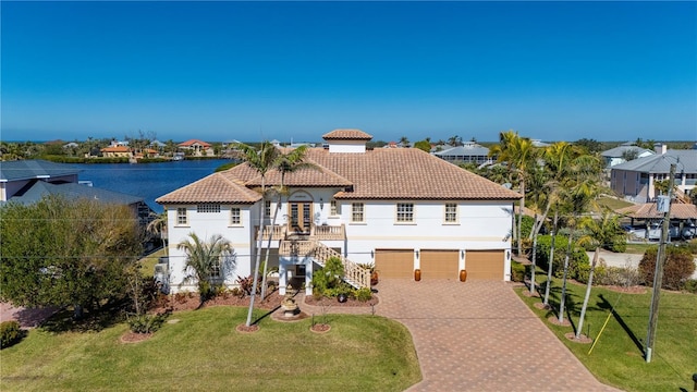 mediterranean / spanish home featuring a garage, a front yard, and a water view