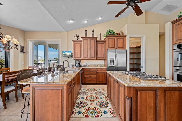 kitchen with sink, a breakfast bar area, light tile patterned floors, appliances with stainless steel finishes, and light stone countertops