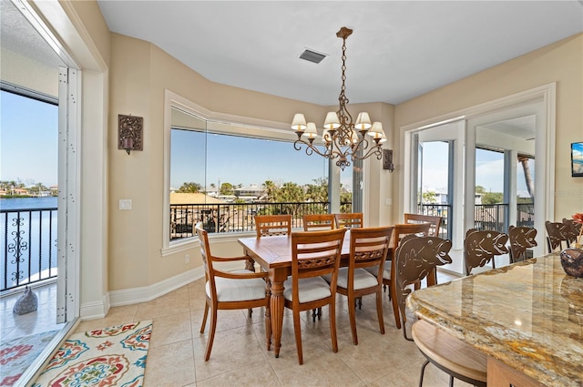 tiled dining room featuring a water view and an inviting chandelier