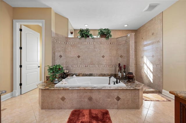 bathroom with tile patterned flooring, vanity, and tiled tub