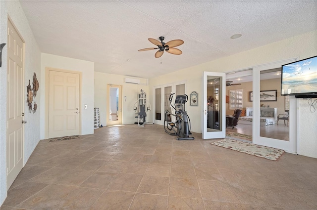 exercise area featuring a wall mounted AC, a textured ceiling, ceiling fan, and french doors