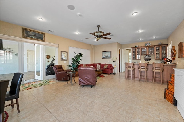 living room with light tile patterned flooring, bar, ceiling fan, and french doors