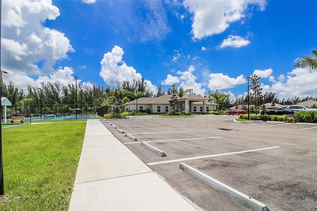 view of parking / parking lot with a yard and tennis court