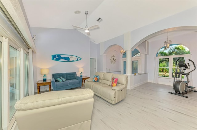 living room featuring arched walkways, visible vents, light wood-style floors, ceiling fan, and high vaulted ceiling