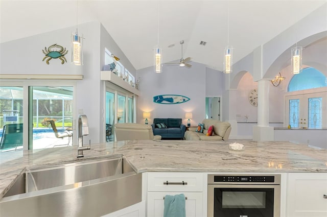 kitchen with hanging light fixtures, white cabinetry, light stone countertops, and sink