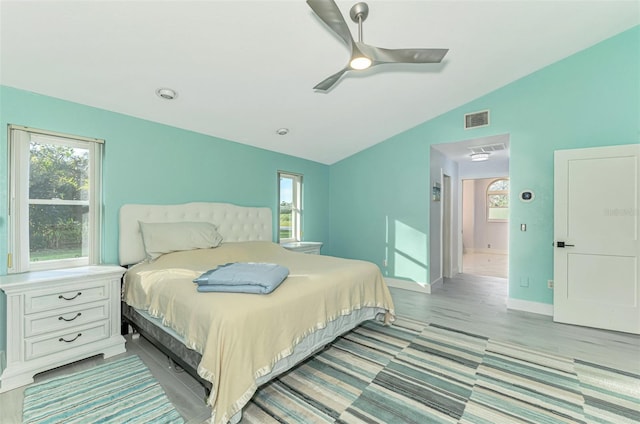 bedroom featuring ceiling fan, light hardwood / wood-style floors, vaulted ceiling, and multiple windows