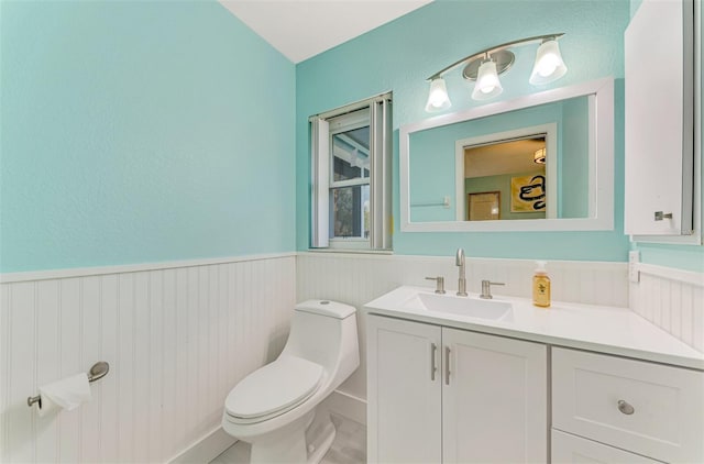 bathroom with a wainscoted wall, vanity, and toilet