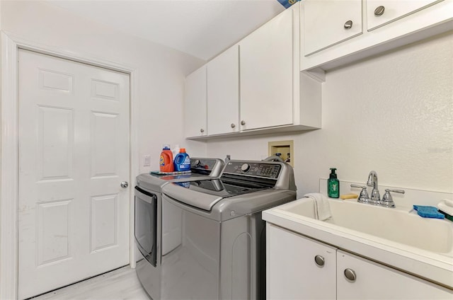 clothes washing area with washer and dryer, cabinet space, and a sink