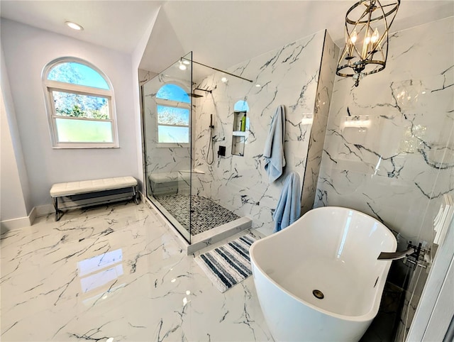 full bathroom with marble finish floor, a notable chandelier, a marble finish shower, a soaking tub, and stone wall