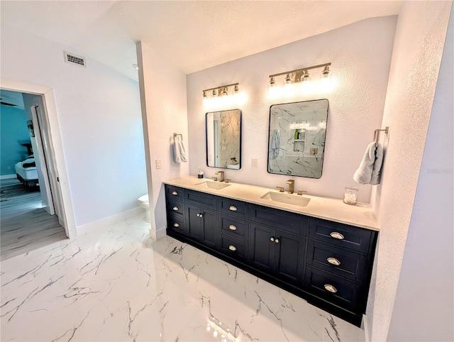 bathroom featuring toilet, a sink, visible vents, baseboards, and marble finish floor