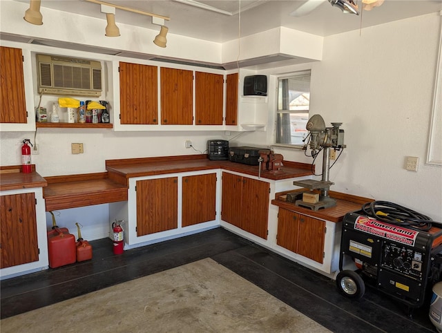 kitchen featuring brown cabinetry, dark countertops, ceiling fan, and a wall mounted AC