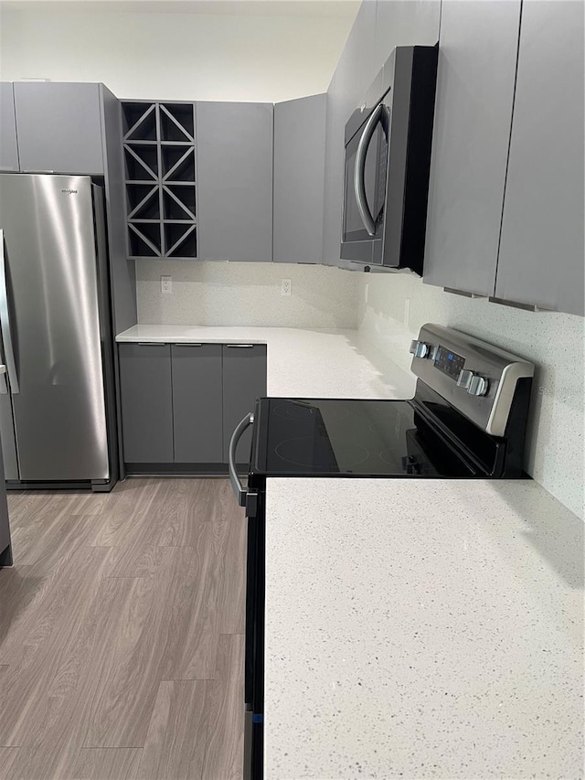 kitchen with stainless steel appliances, gray cabinets, and light hardwood / wood-style floors