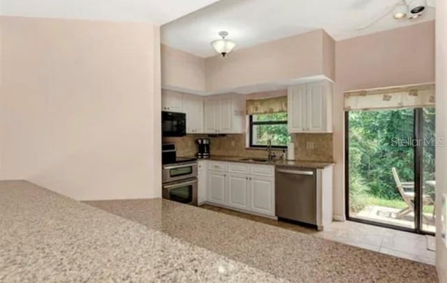 kitchen featuring sink, appliances with stainless steel finishes, tasteful backsplash, white cabinets, and stone countertops