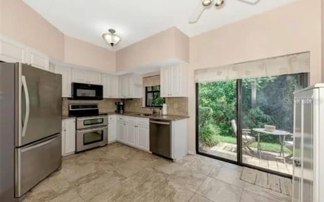 kitchen featuring appliances with stainless steel finishes, sink, white cabinets, backsplash, and ceiling fan