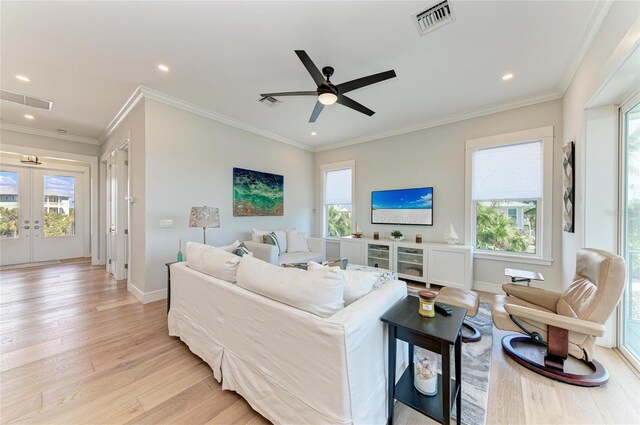 living room with crown molding, plenty of natural light, light hardwood / wood-style floors, and french doors