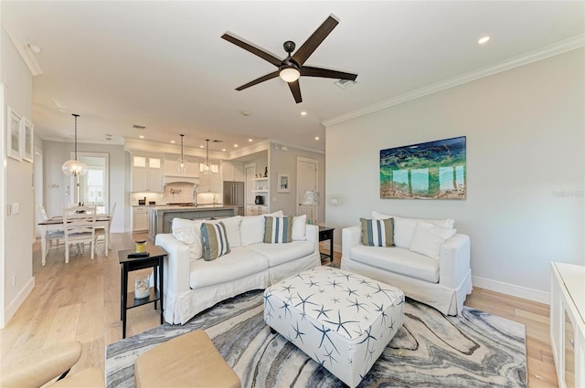 living room featuring ornamental molding, sink, ceiling fan, and light hardwood / wood-style floors