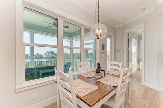 dining area with light hardwood / wood-style flooring, ornamental molding, a healthy amount of sunlight, and a water view