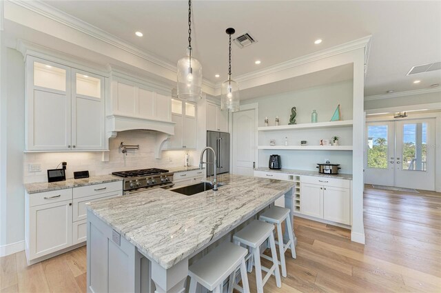 kitchen with white cabinetry, sink, a center island with sink, and premium appliances