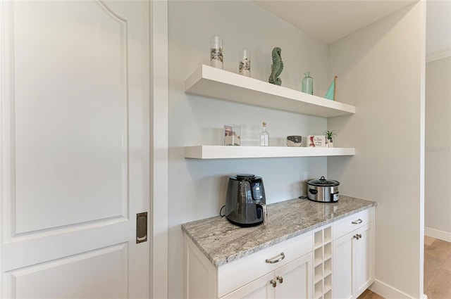 bar with light stone countertops and white cabinets
