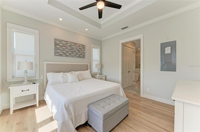 bedroom featuring ornamental molding, a raised ceiling, electric panel, and light wood-type flooring