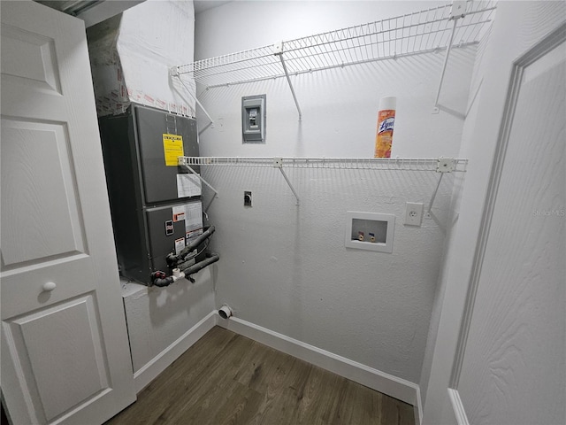 laundry room featuring electric dryer hookup, dark wood-type flooring, washer hookup, and heating unit