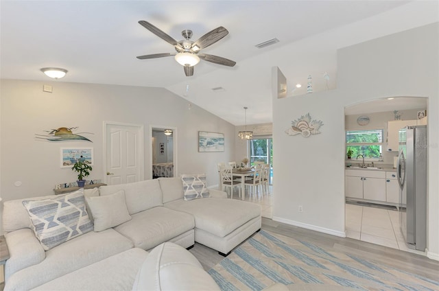 living room with ceiling fan, lofted ceiling, sink, and a wealth of natural light