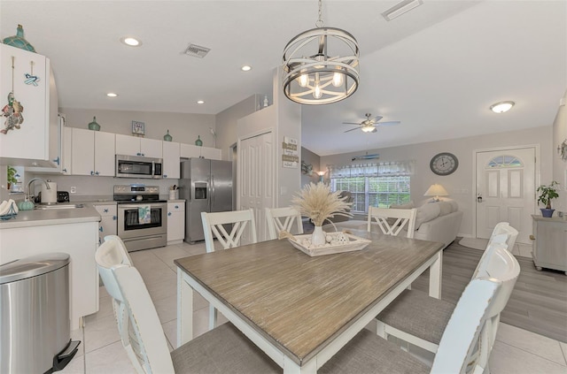 dining space featuring sink, ceiling fan with notable chandelier, and light tile patterned flooring