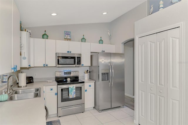 kitchen with lofted ceiling, sink, light tile patterned floors, appliances with stainless steel finishes, and white cabinets