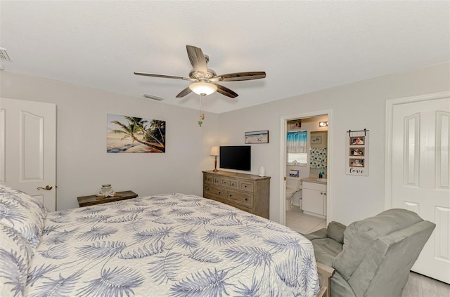 bedroom featuring ensuite bathroom, light tile patterned flooring, and ceiling fan