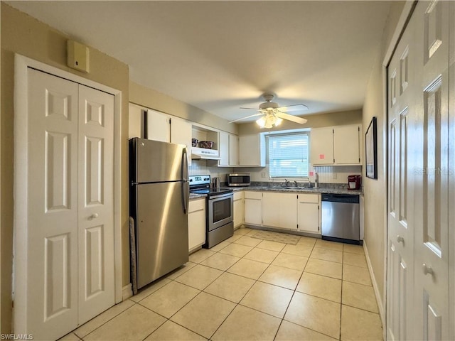 kitchen with appliances with stainless steel finishes, white cabinetry, sink, light tile patterned floors, and ceiling fan