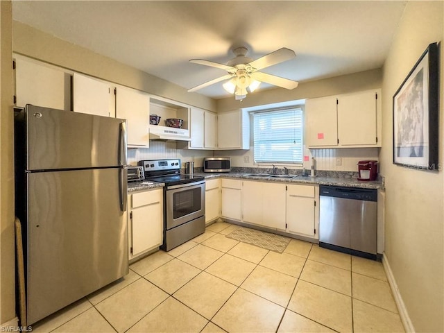 kitchen with stainless steel appliances, sink, light tile patterned floors, and white cabinets