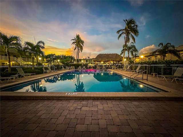 pool at dusk featuring a patio