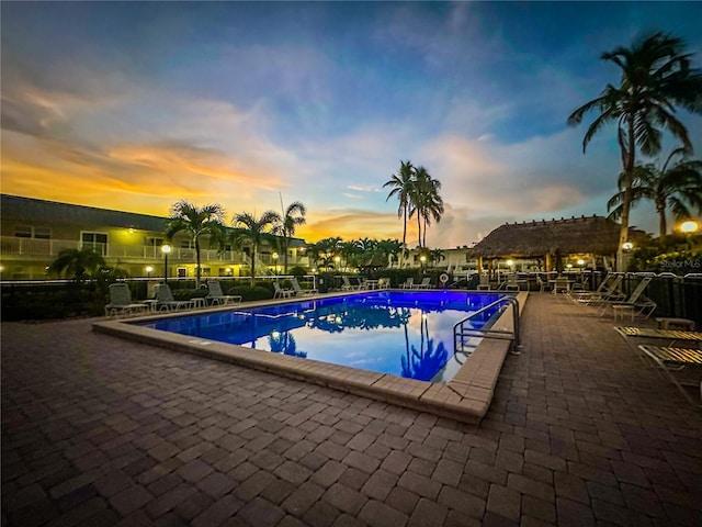 pool at dusk featuring a patio