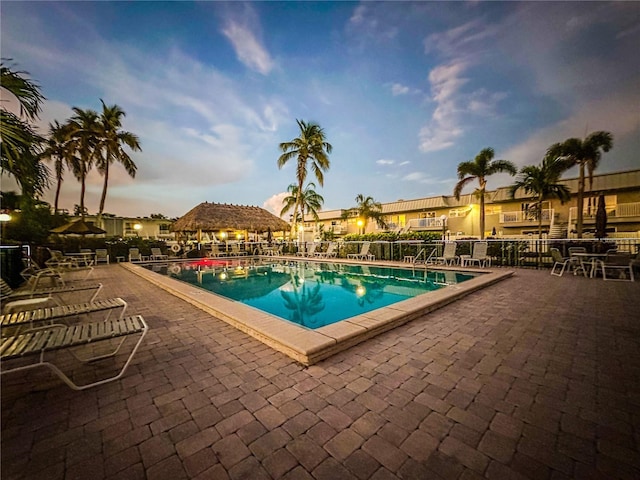 pool at dusk with a gazebo and a patio area