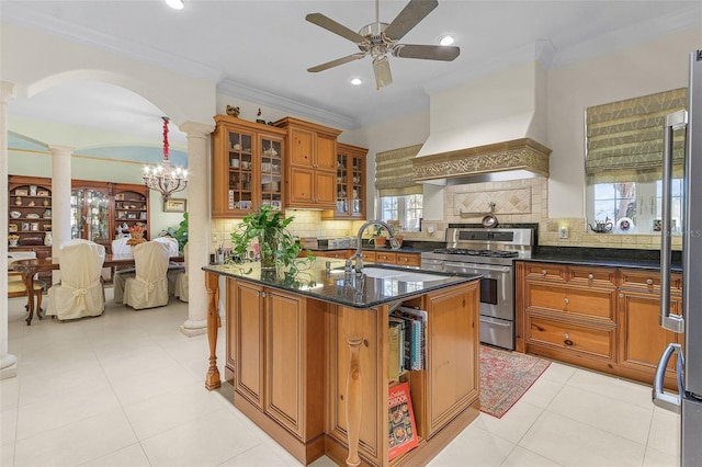 kitchen featuring sink, appliances with stainless steel finishes, dark stone countertops, custom range hood, and a center island with sink