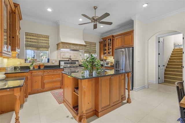 kitchen with appliances with stainless steel finishes, dark stone countertops, backsplash, a center island, and custom range hood