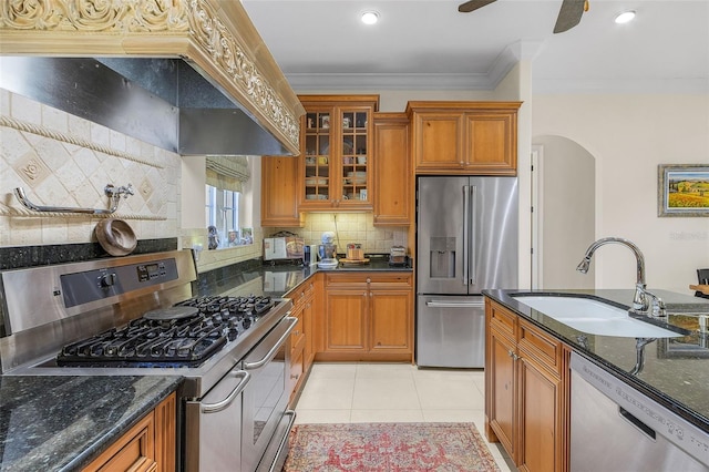 kitchen with appliances with stainless steel finishes, sink, dark stone countertops, crown molding, and custom range hood