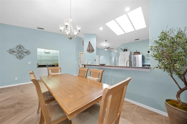 dining room with ceiling fan with notable chandelier and a skylight