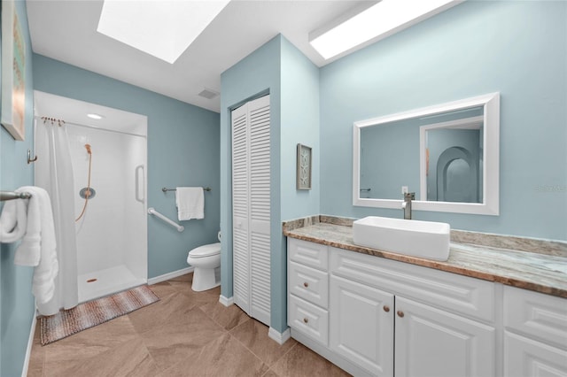 bathroom with tile patterned flooring, a skylight, vanity, a shower, and toilet